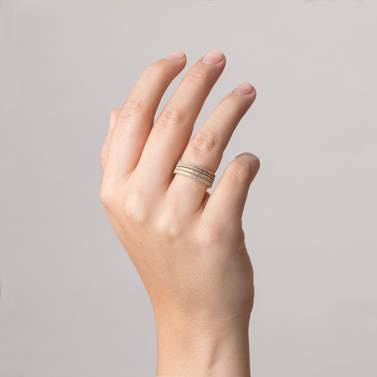 Model.  close up of hand wearing four gold rings 