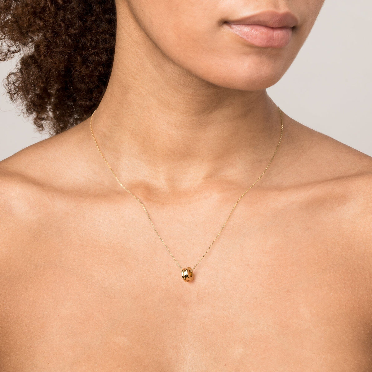 Model Close-up of a woman wearing a delicate gold chain necklace featuring a small gold column pendant