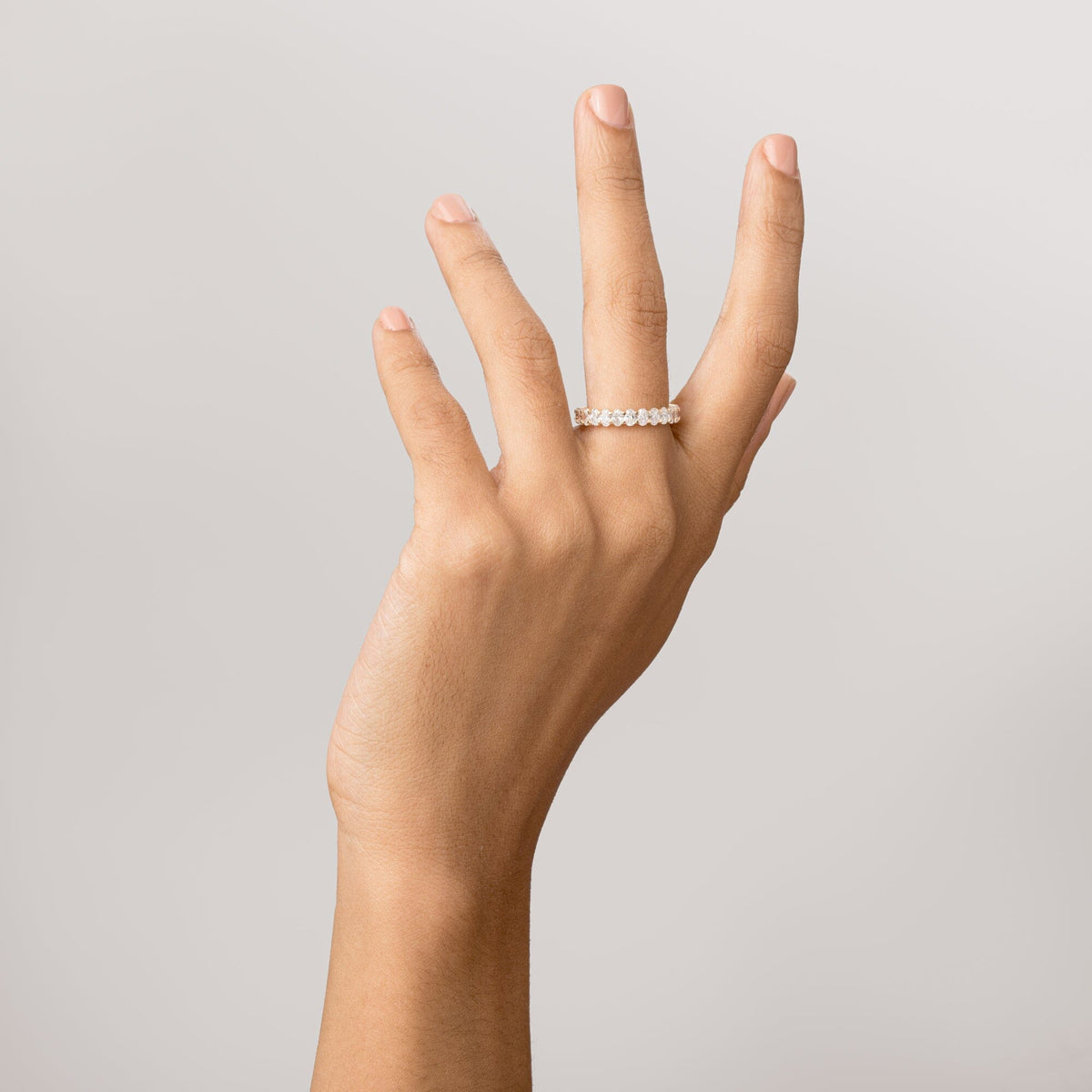 Model Close-up of a woman's hand with fingers gently curled upward, wearing a gold oval diamond eternity ring.