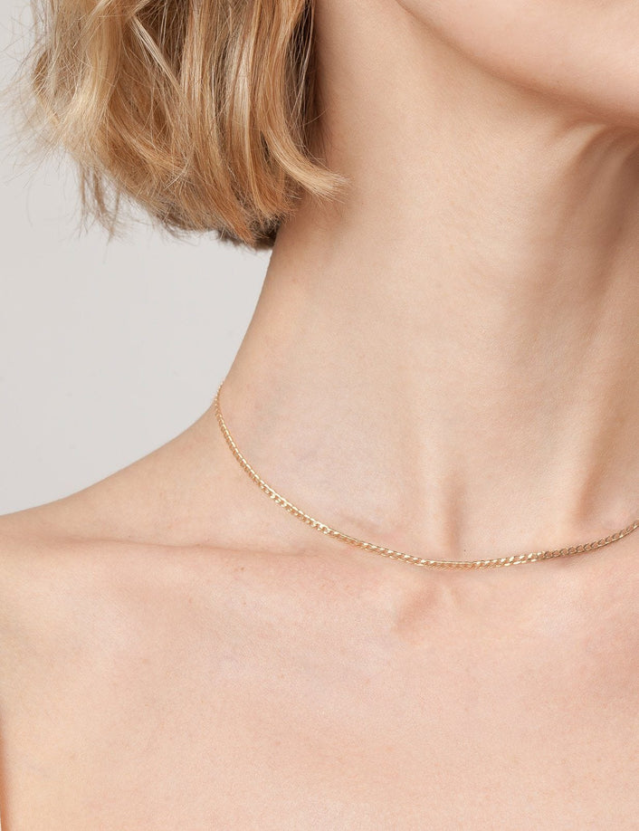 Model. Close up of woman wearing gold chain necklace on white background