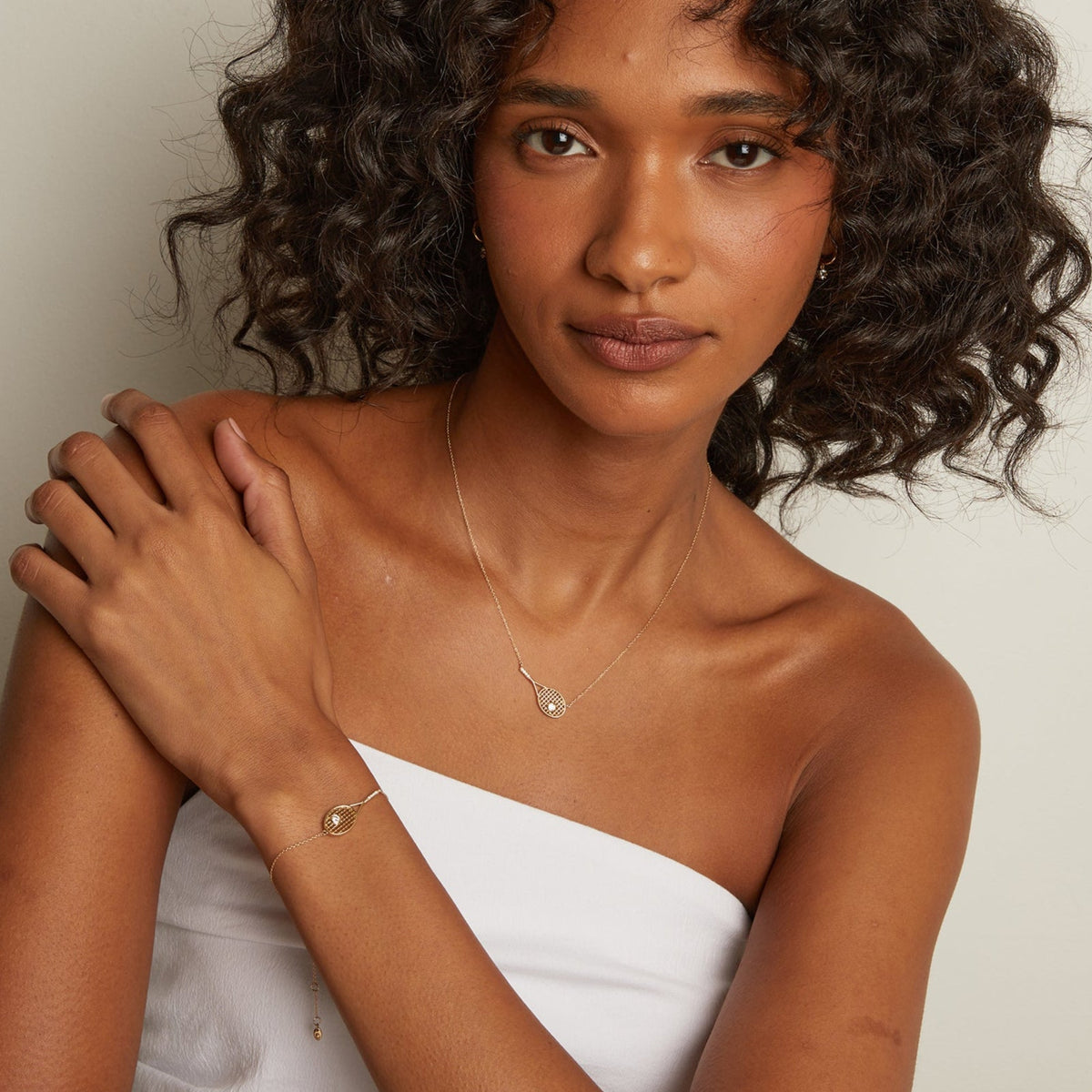 Woman wearing gold jewelry against a neutral background