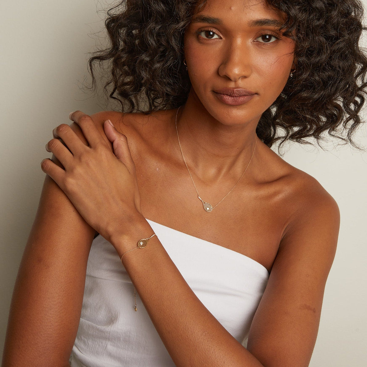 Model. Woman with curly hair wearing a white strapless top against a plain background