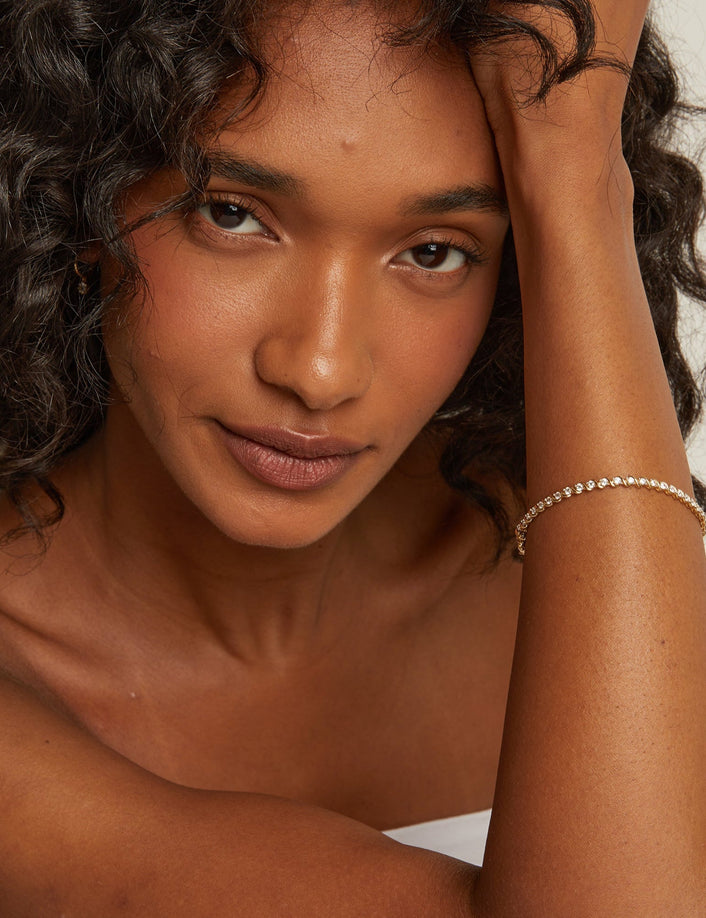 Model. Woman with curly hair touching her head against a plain background