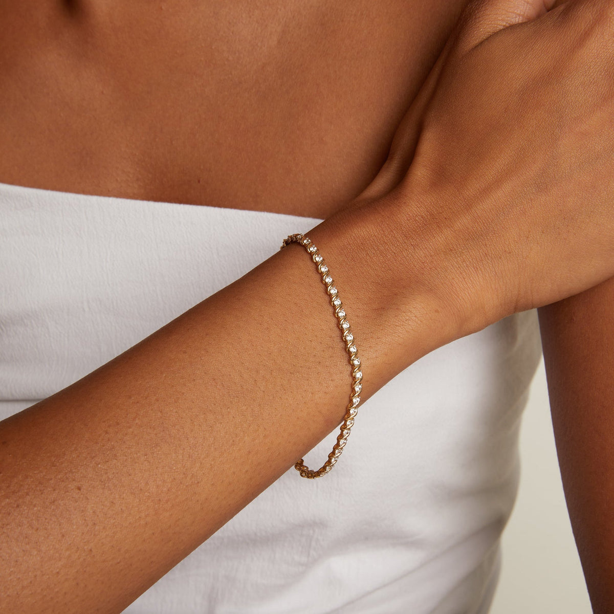 Model. Gold bracelet on a wrist with a neutral background