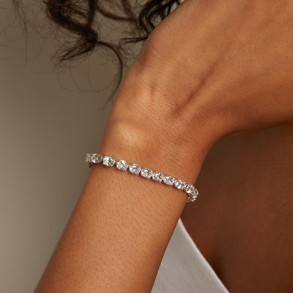 Model. Close-up of a person wearing a silver bracelet on a neutral background