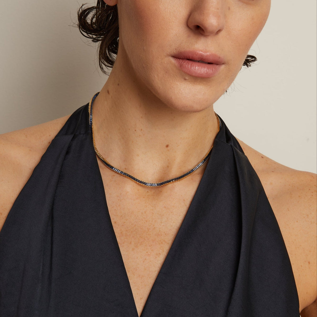 Model. Woman wearing a black halter neck dress against a neutral background
