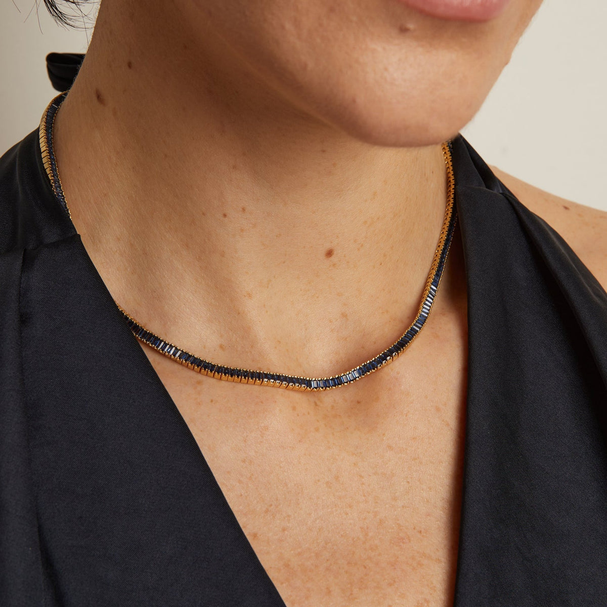 Model. Close-up of a person wearing a delicate necklace with a neutral background