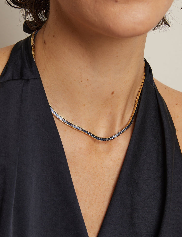 Person wearing a gold necklace with a plain background