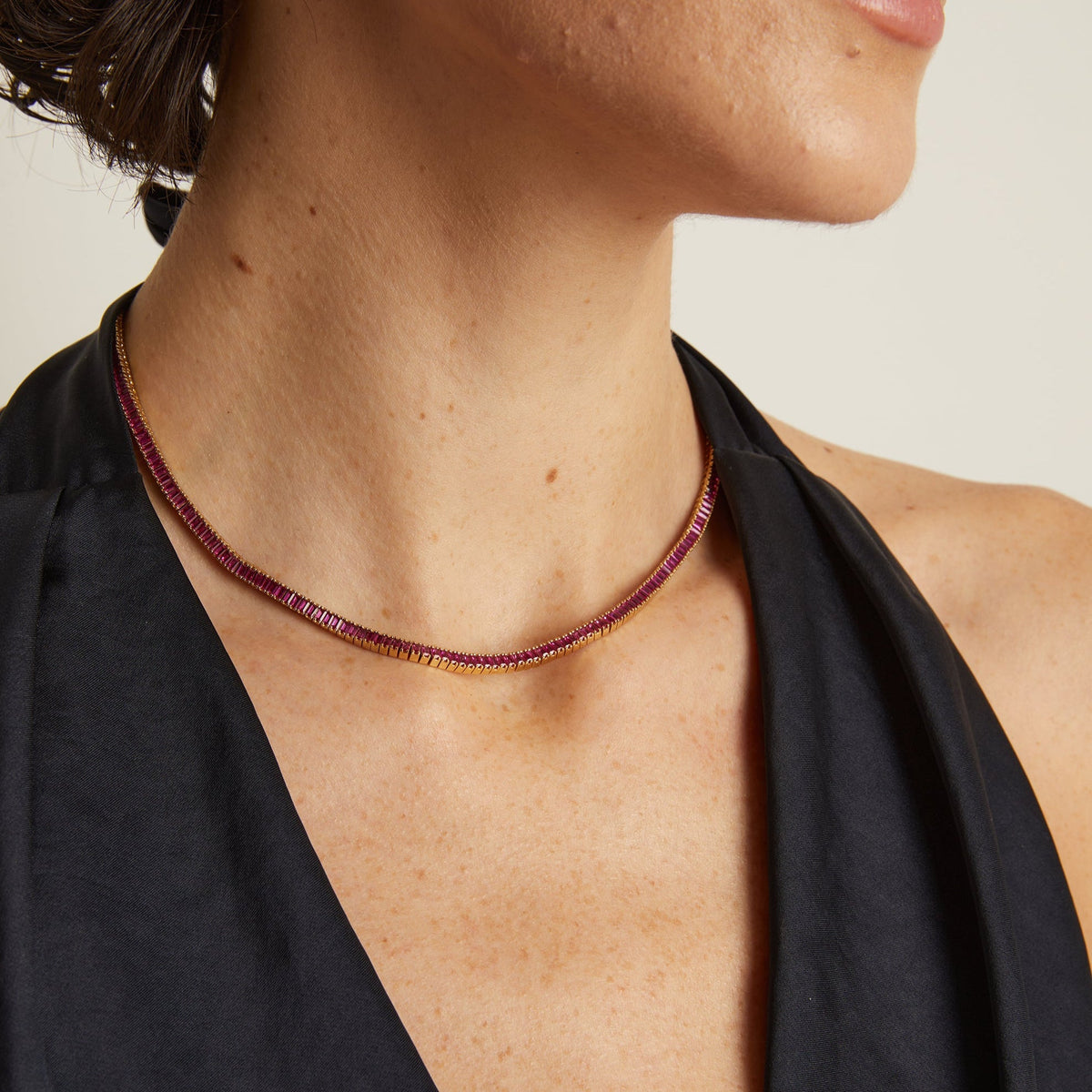 Model. Close-up of a person wearing a delicate necklace with a plain background