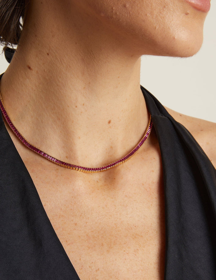 Close-up of a person wearing a necklace with a neutral background