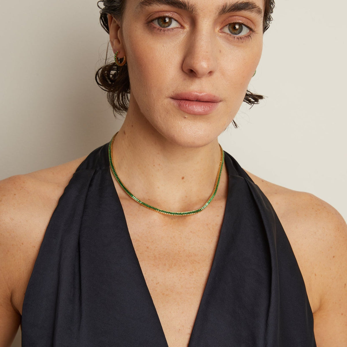 Model. Woman wearing a black halter neck dress against a plain background