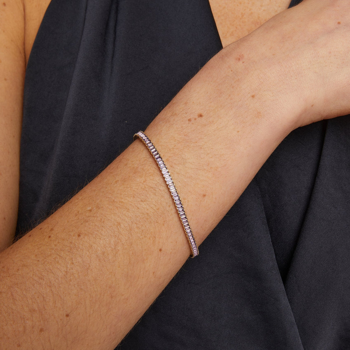 Model. Person wearing a black garment with a bracelet on a neutral background