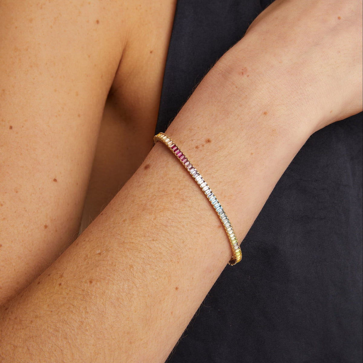 Model. Close-up of a person's arm wearing a colorful beaded bracelet against a black background