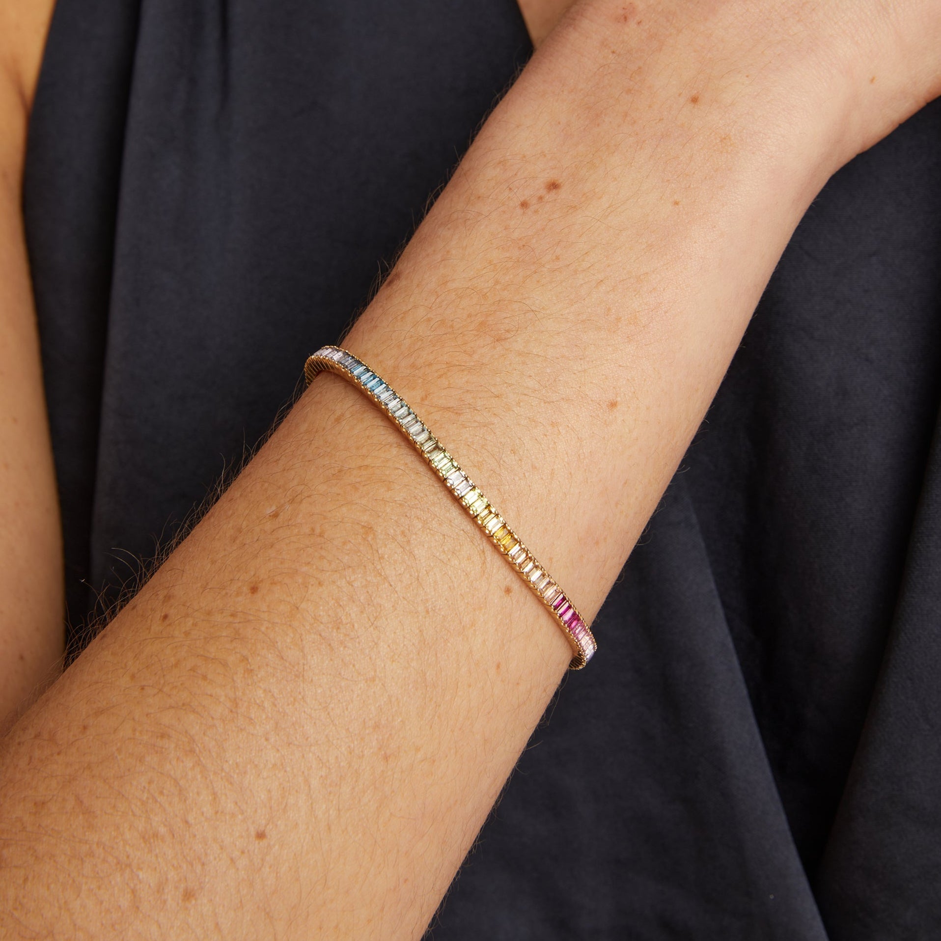 Multicolored beaded bracelet on a person's wrist against a black background