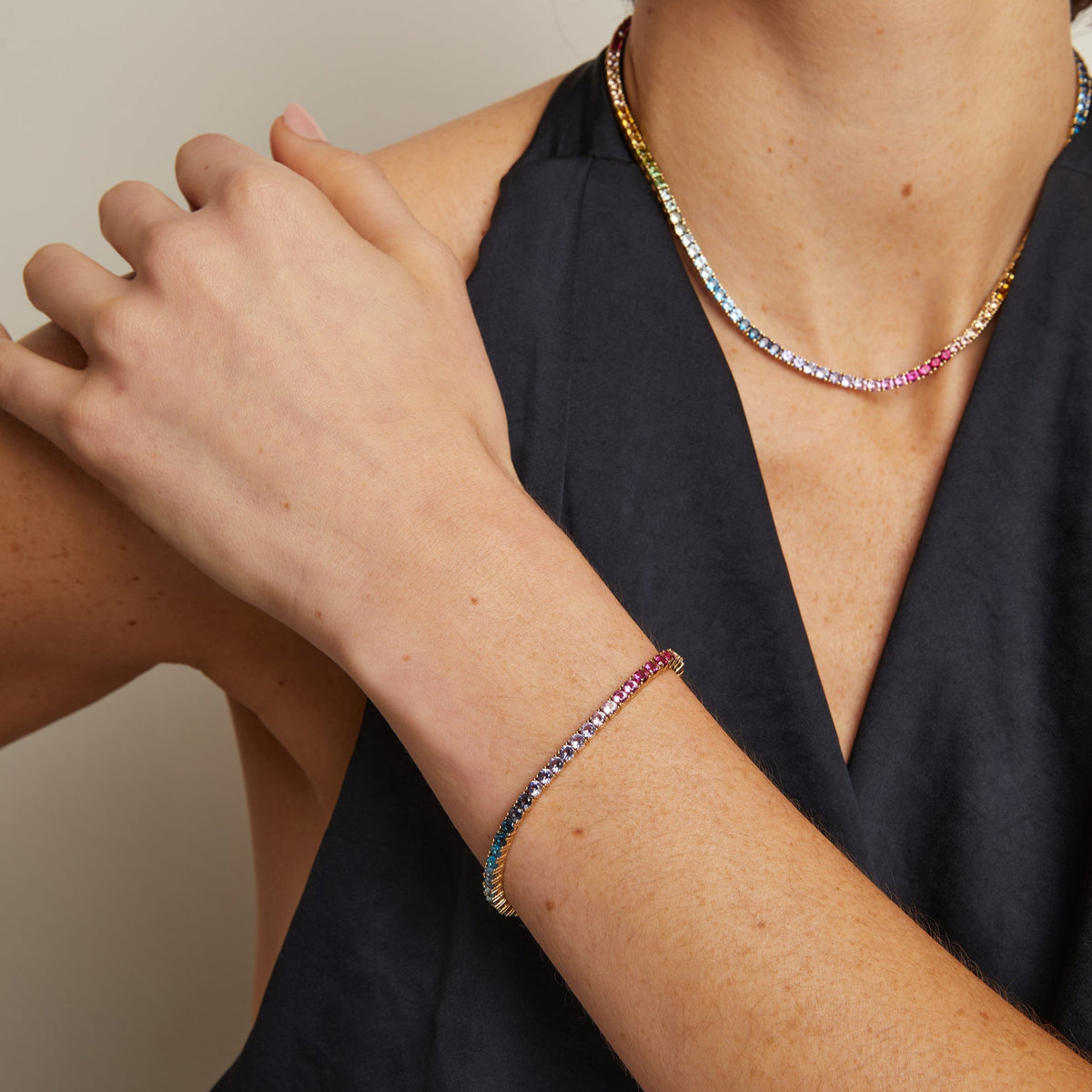 Model. Person wearing a colorful beaded bracelet and necklace against a neutral background