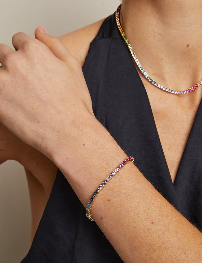 Person wearing a colorful beaded bracelet and necklace on a neutral background