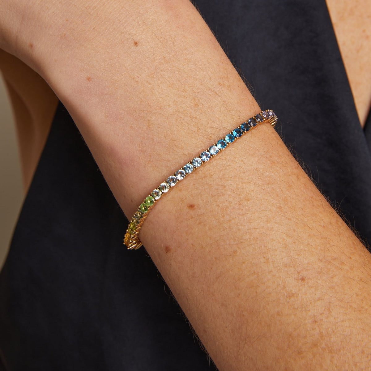 Model. Close-up of a person's arm wearing a colorful beaded bracelet on a plain background