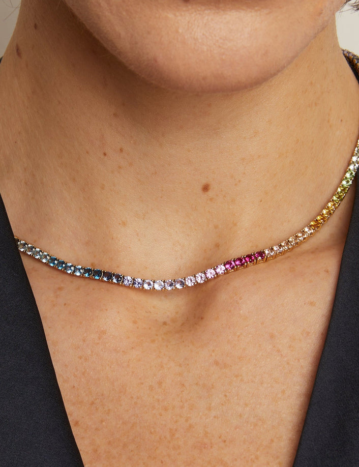 Necklace with multicolored gemstones worn by a person against a neutral background