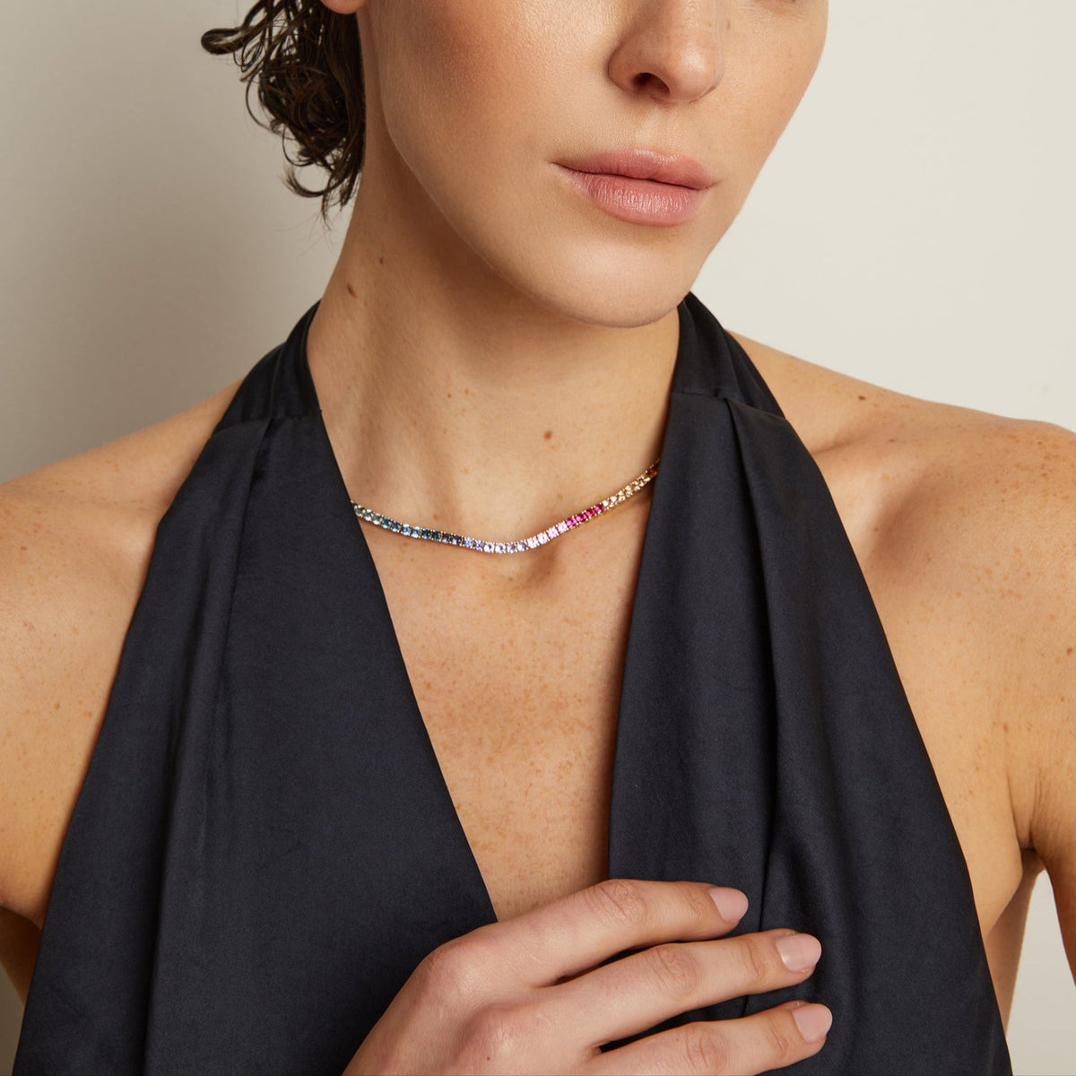 Model. Person wearing a black top with a necklace against a neutral background