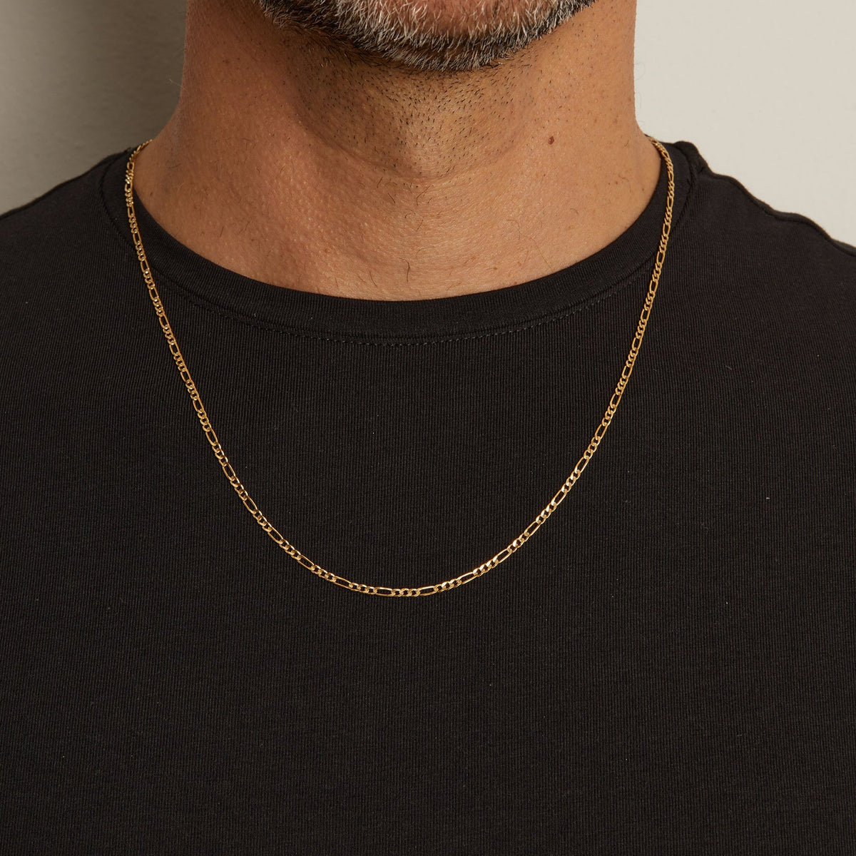 Model. Close up of man wearing gold chain necklace over a black t shirt