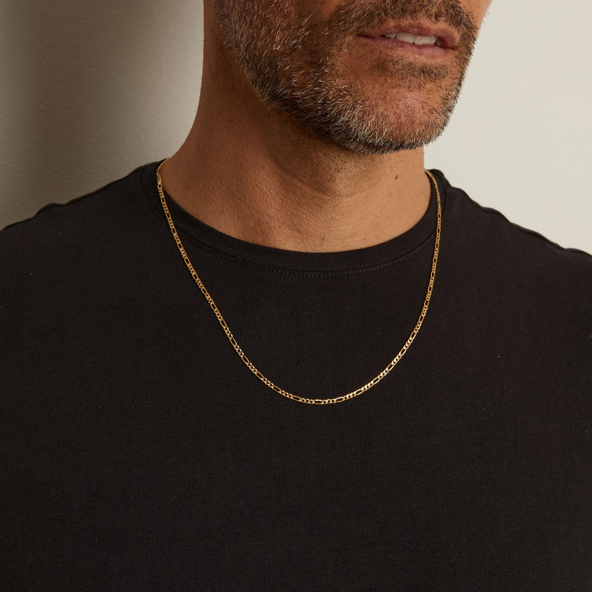 Model. Close up of man wearing gold chain necklace over a black t shirt