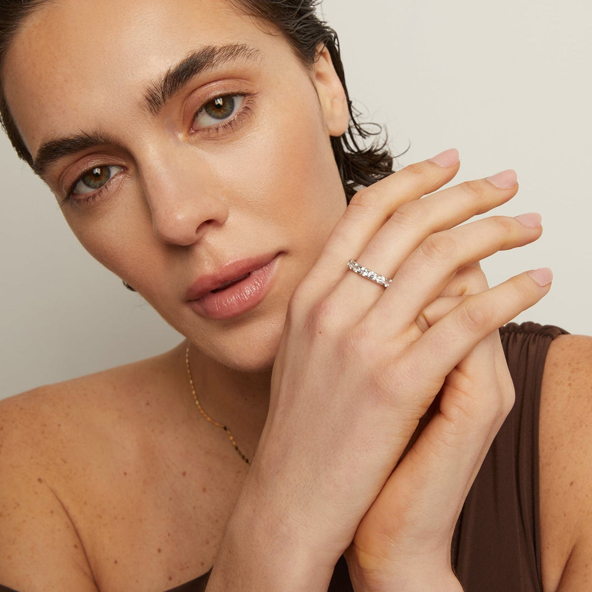 Model. Woman wearing a ring on her finger with a neutral background