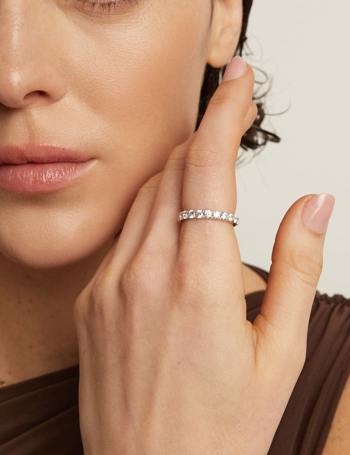 Close-up of a woman wearing a silver ring with a beige background