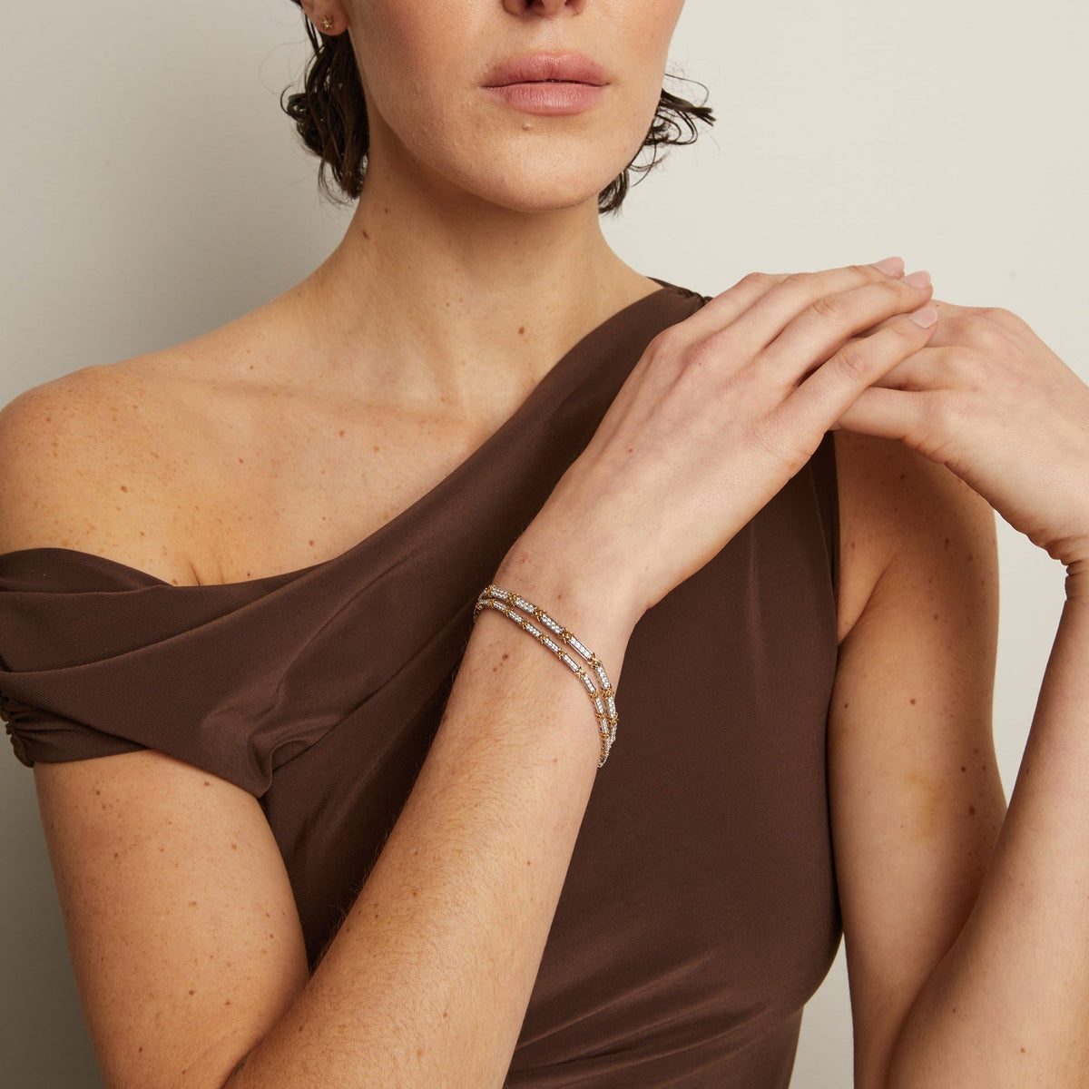 Model. Woman wearing a brown off-shoulder top against a plain background