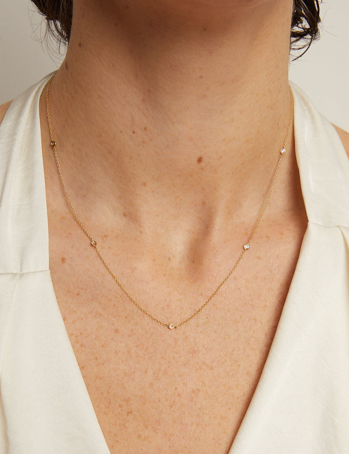 Gold necklace worn by a person with a neutral background