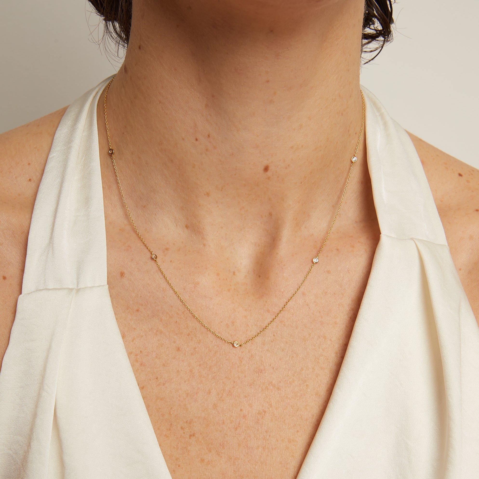 Gold necklace worn by a person with a neutral background
