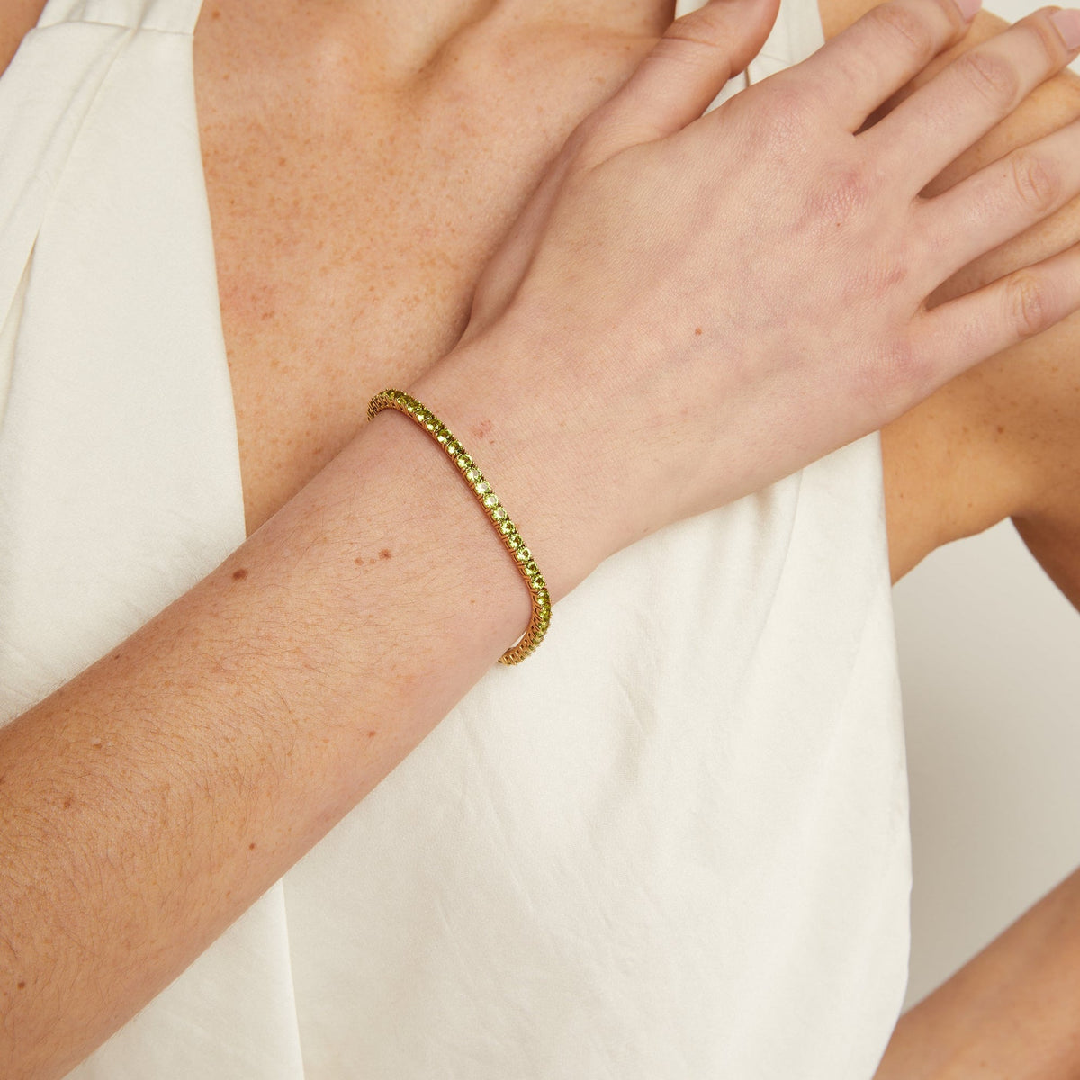 Model. Person wearing a gold bracelet on a plain background