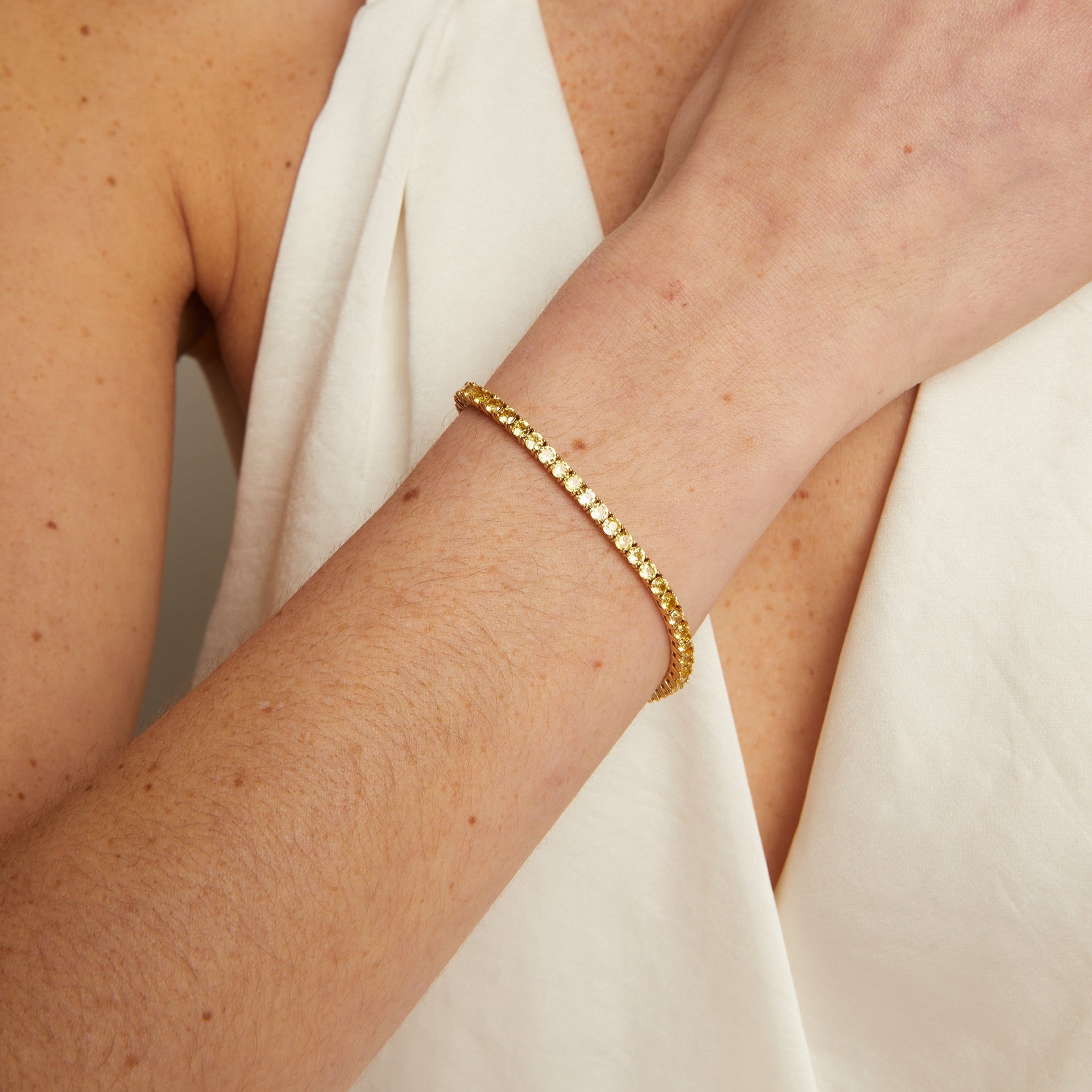 Gold bracelet on a person's wrist with a neutral background