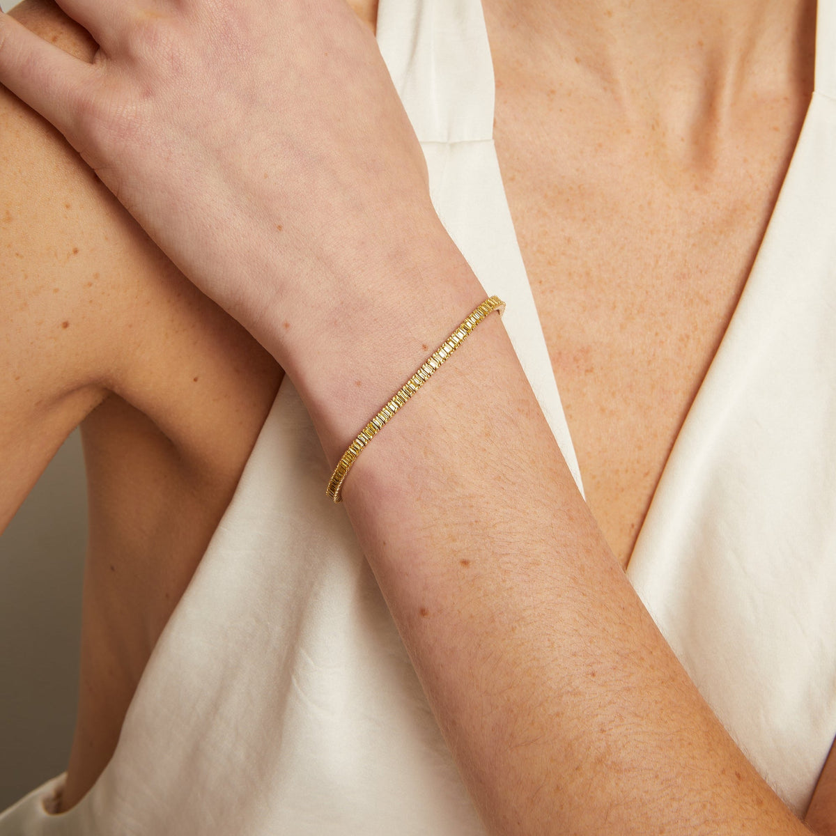 Model. Gold bracelet on a person's wrist with a neutral background