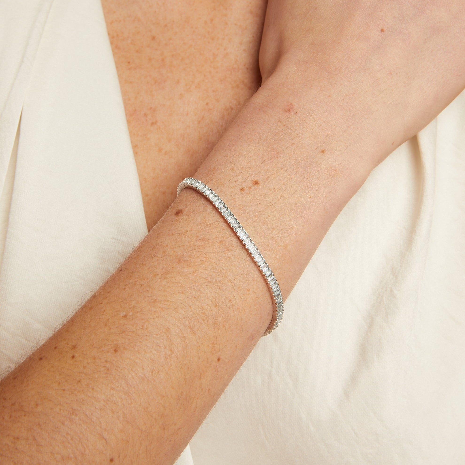 Silver bracelet on a person's wrist with a plain background