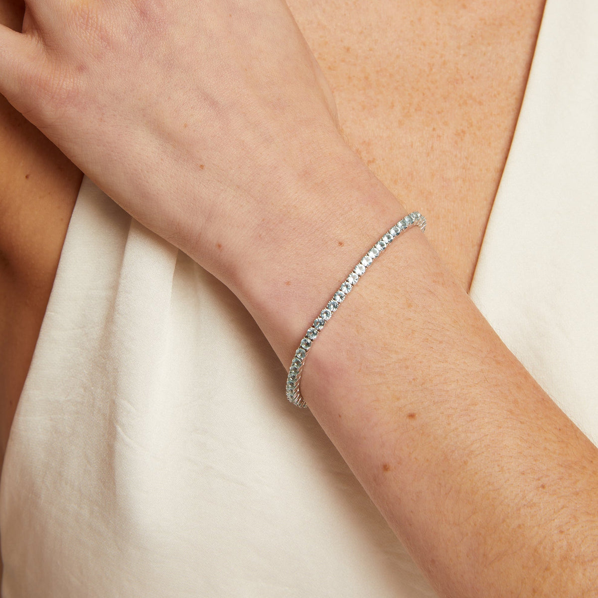 Silver bracelet on a person's wrist with a neutral background