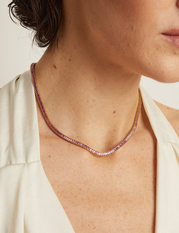 Close-up of a woman wearing a delicate necklace with a plain background