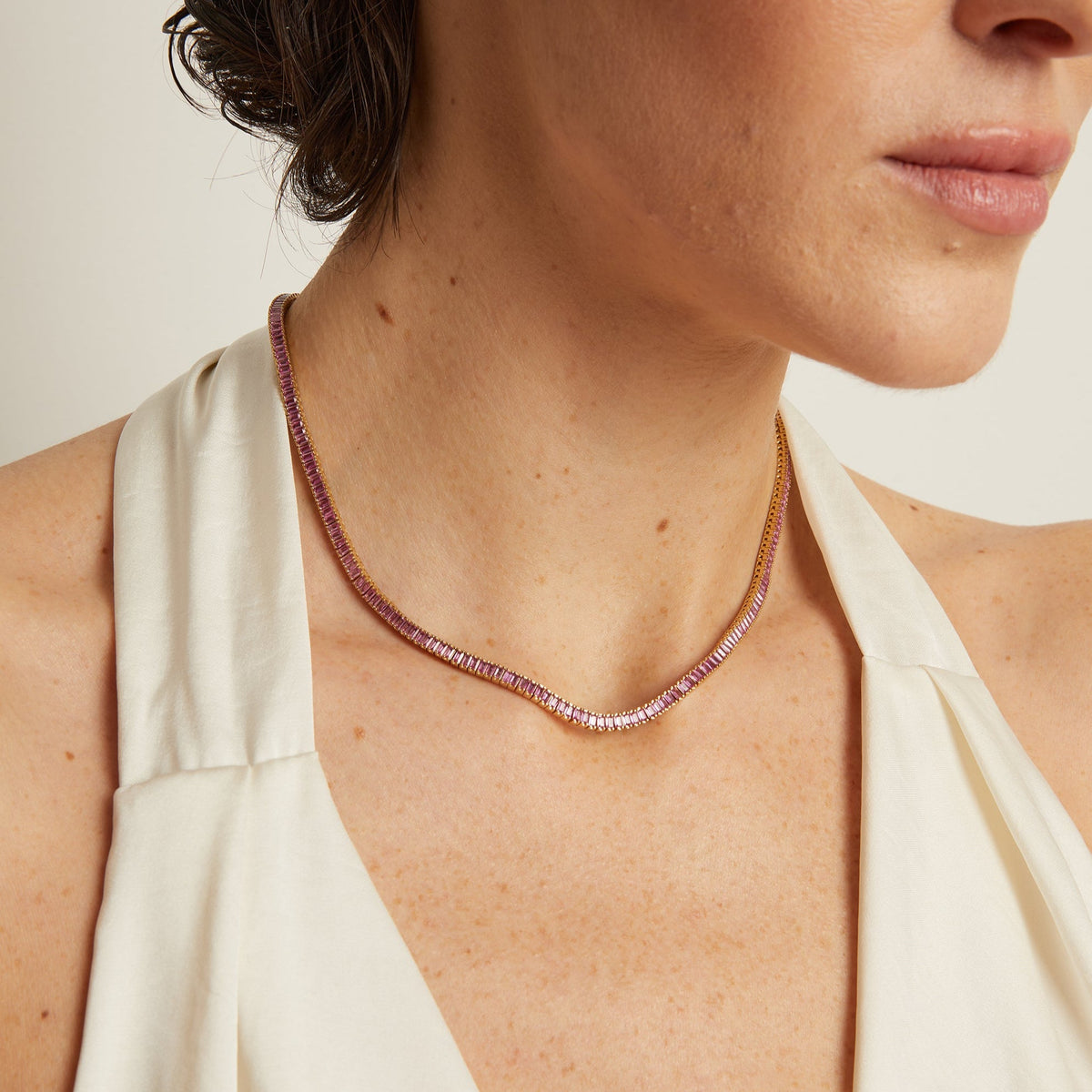 Close-up of a woman wearing a delicate necklace with a plain background