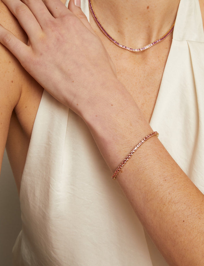 Close-up of a person wearing a beaded bracelet and necklace on a neutral background