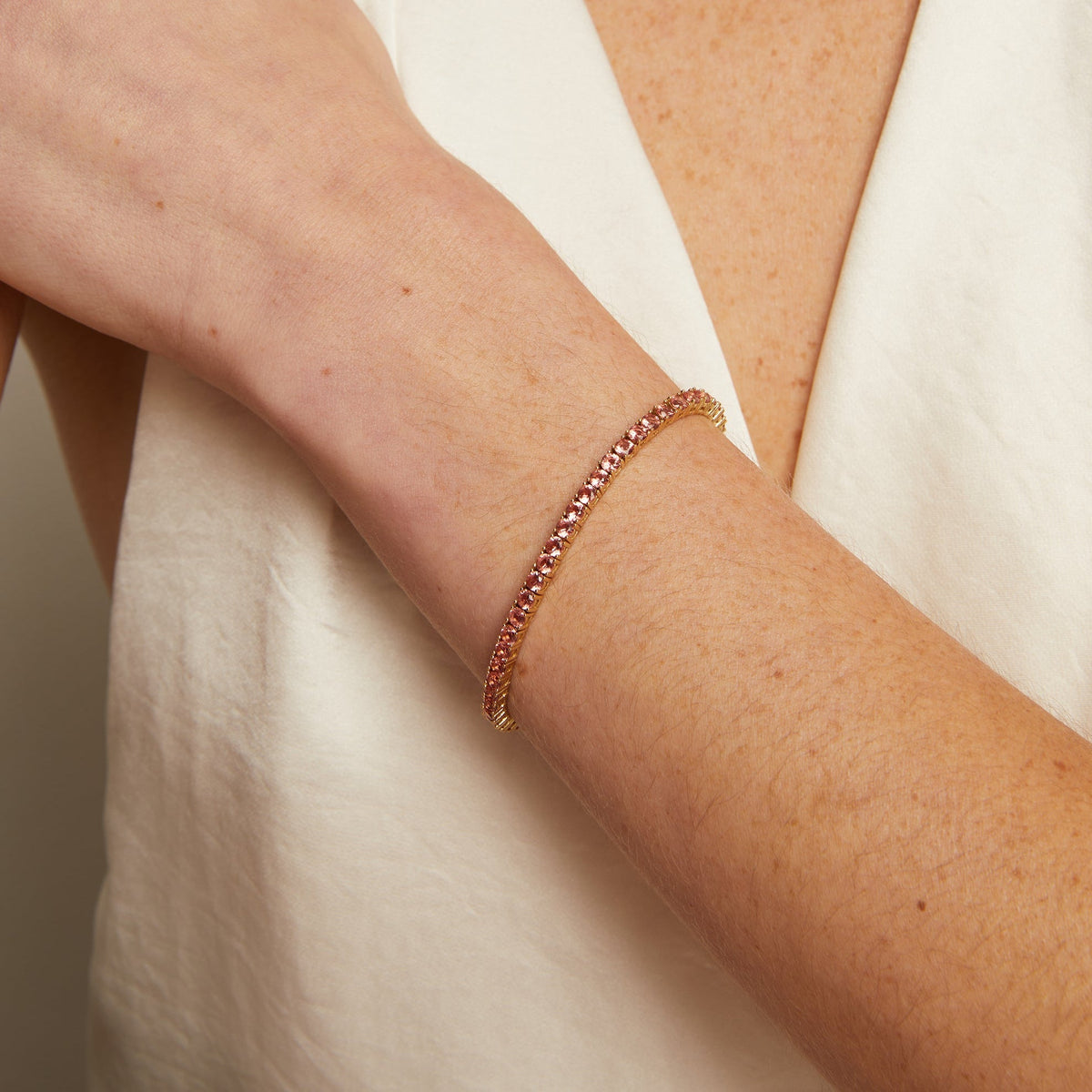 Model. Close-up of a person wearing a beaded bracelet and necklace against a neutral background