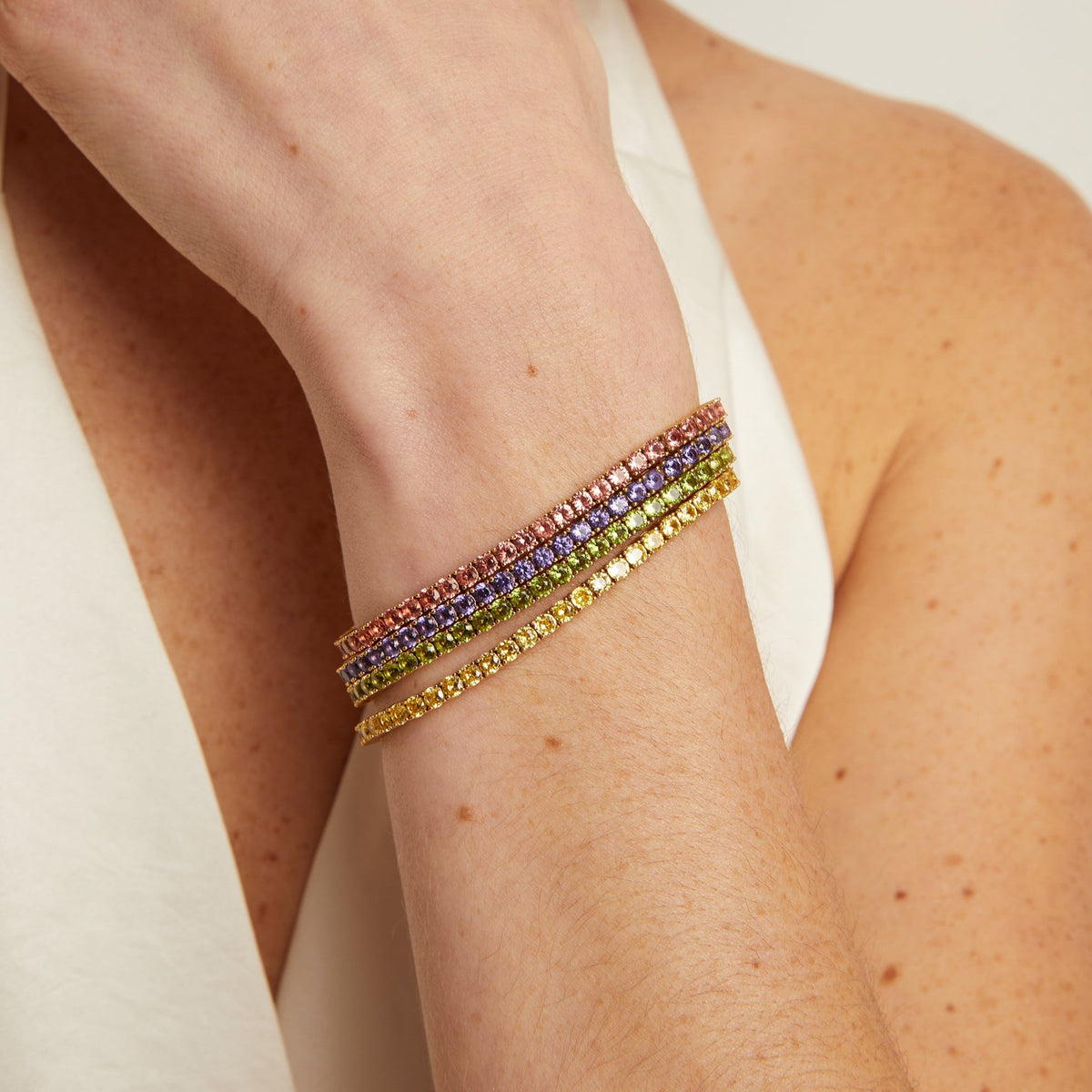Model. Close-up of a person's arm wearing colorful beaded bracelets on a neutral background