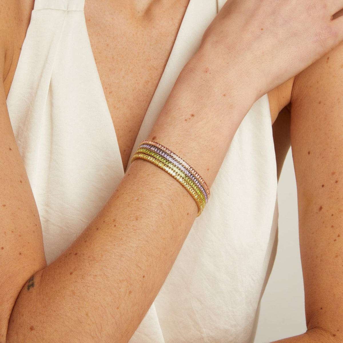 Close-up of a person's arm wearing a colorful bracelet on a neutral background