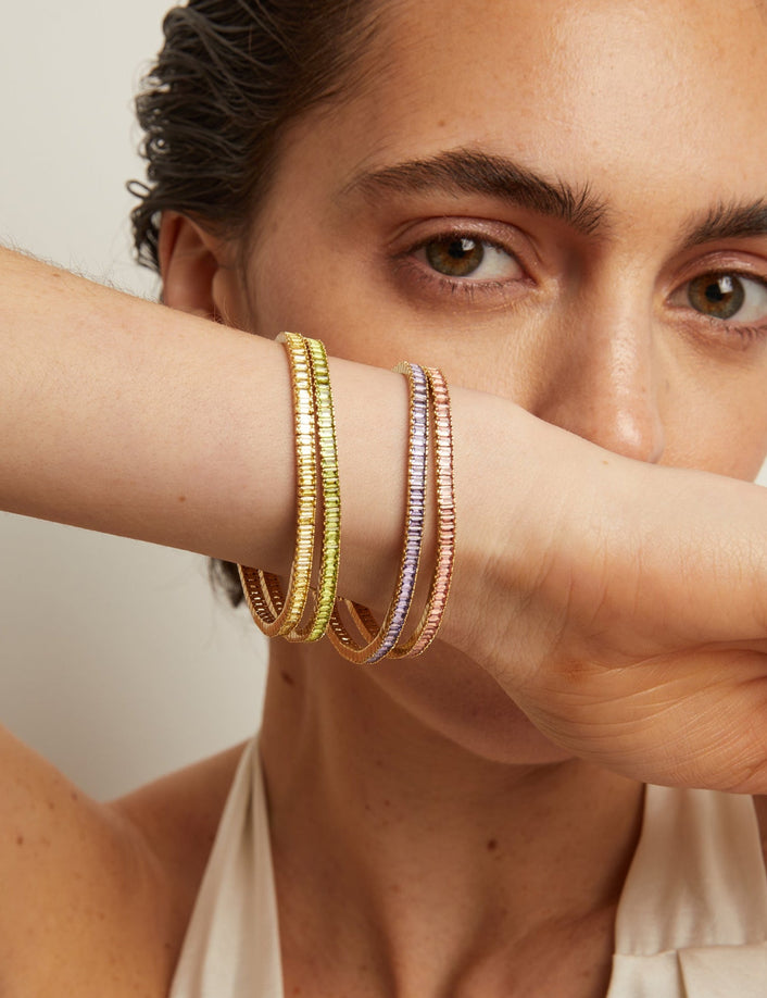 Close-up of a person wearing colorful bracelets on a neutral background