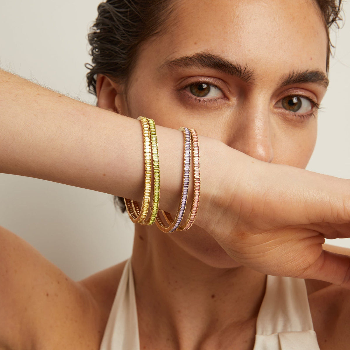 Model. Woman wearing multiple bracelets on her wrist with a neutral background