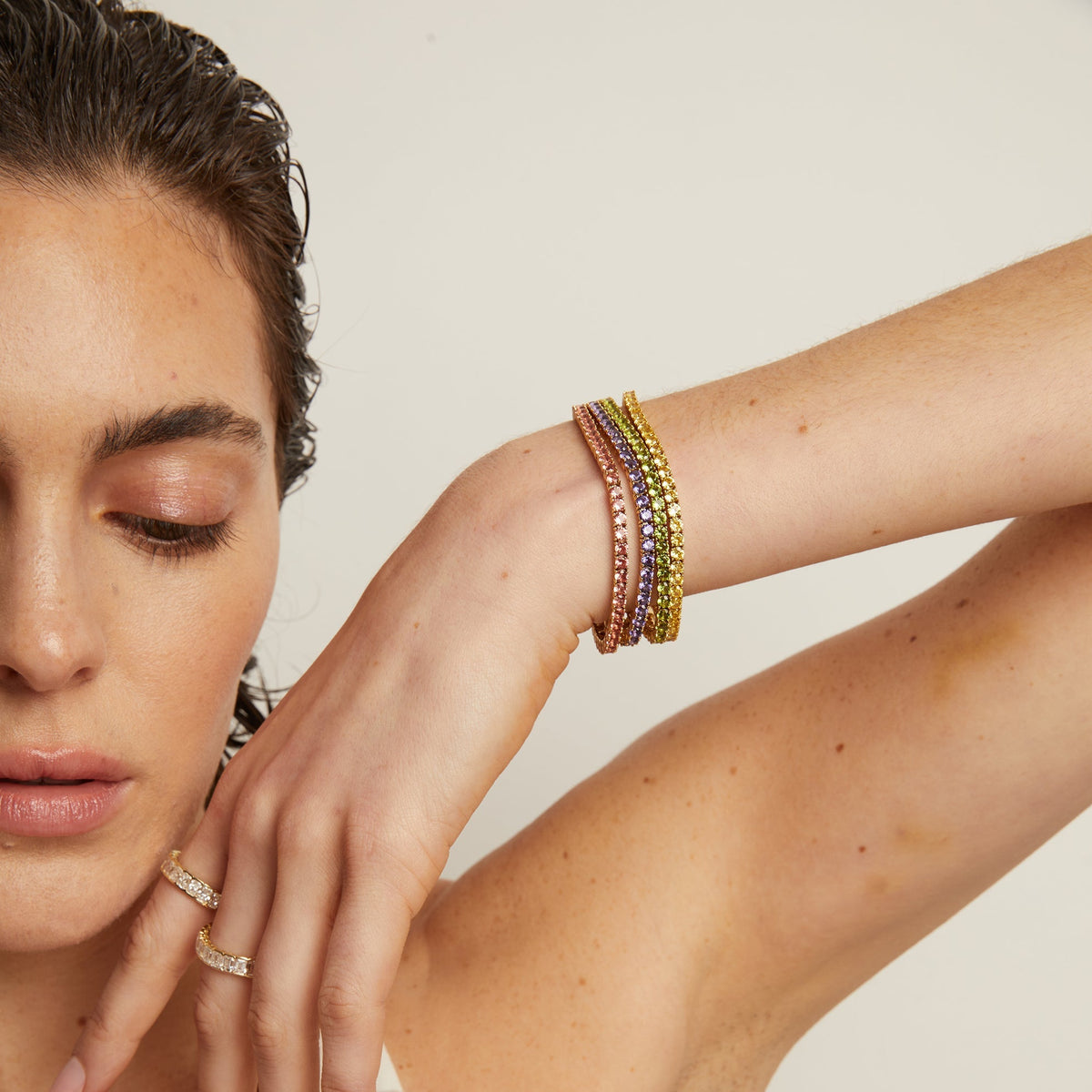 Model. Woman wearing colorful bracelets on a neutral background